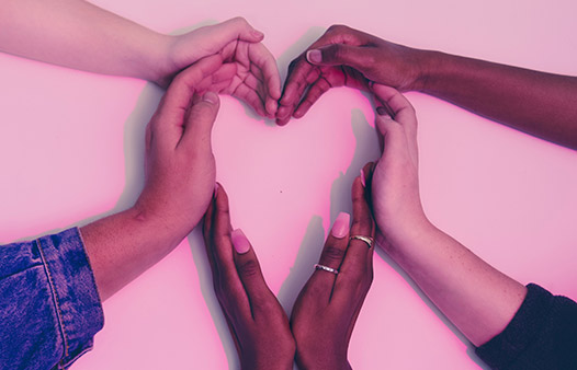 six hands of different colour come together to form a heart